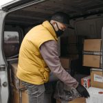 Movers carefully load labeled boxes and furniture into a moving truck parked outside a residential home.