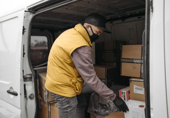 Movers carefully load labeled boxes and furniture into a moving truck parked outside a residential home.