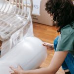A mover carefully wraps an antique wooden table with protective padding inside a residential living room before a move.