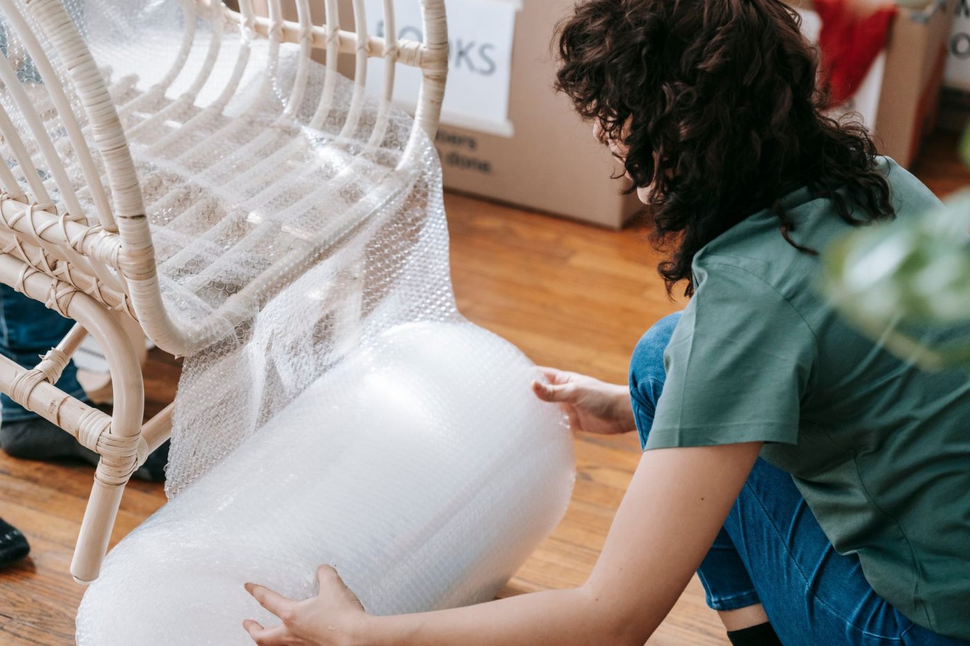 A mover carefully wraps an antique wooden table with protective padding inside a residential living room before a move.