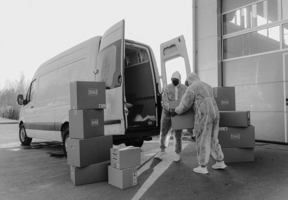 A mover carries a cardboard box toward a moving truck parked outside a residential home.