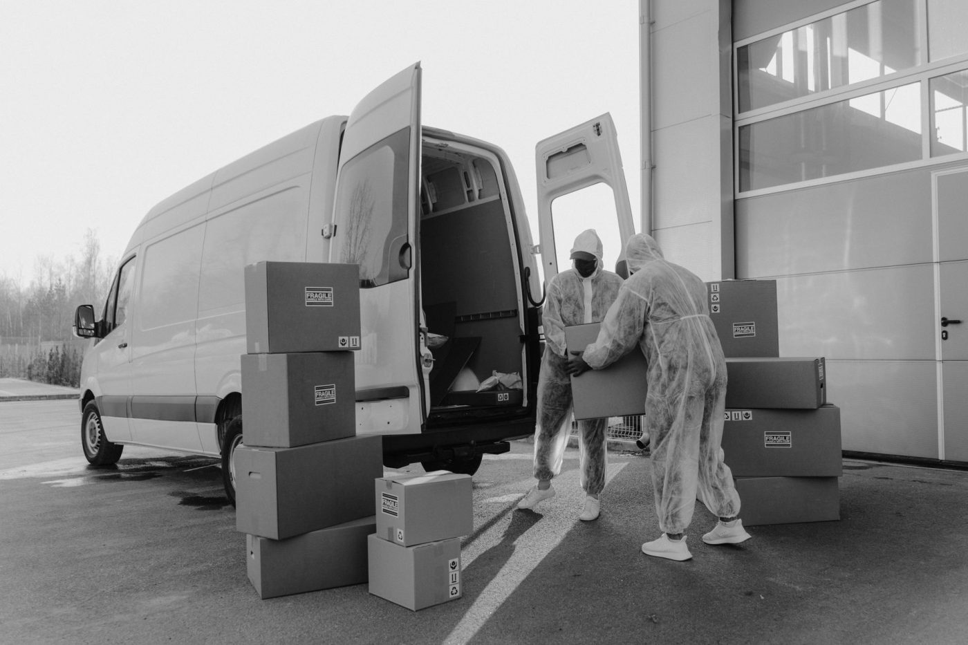 A mover carries a cardboard box toward a moving truck parked outside a residential home.