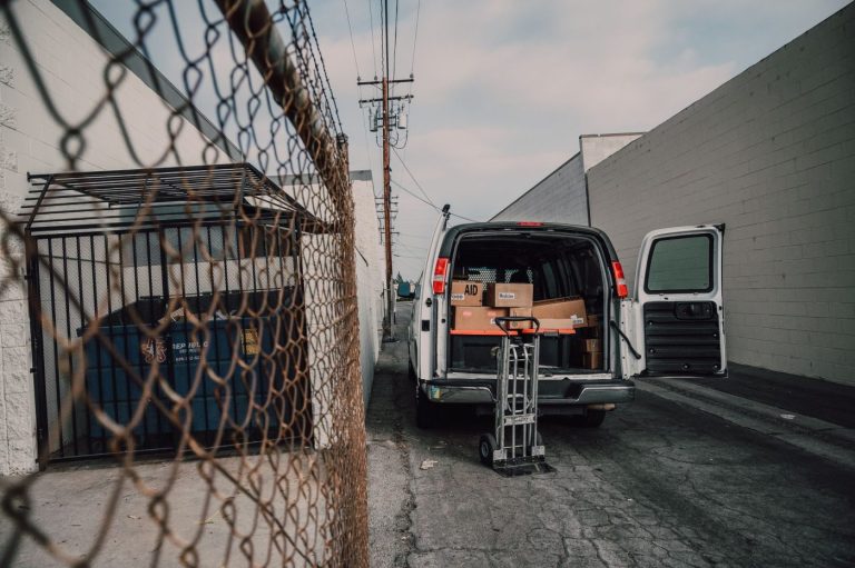 Movers carrying furniture and boxes into a moving truck parked in front of a house on a sunny day.