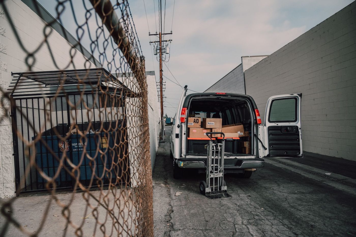 Movers carrying furniture and boxes into a moving truck parked in front of a house on a sunny day.