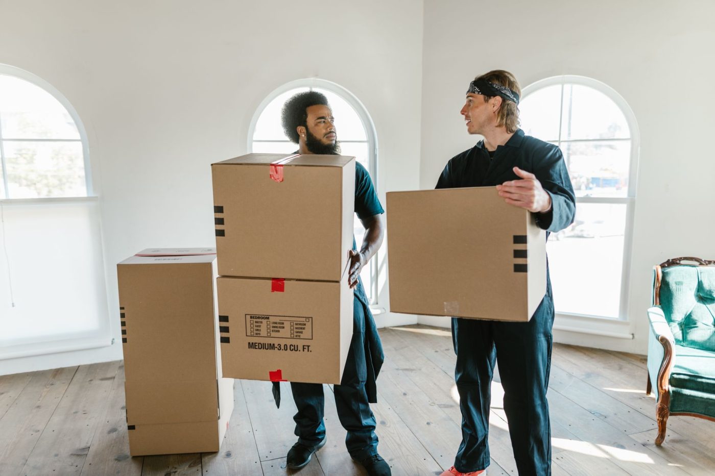 Movers carefully wrapping a grand piano with protective blankets inside a residential living room before a move.